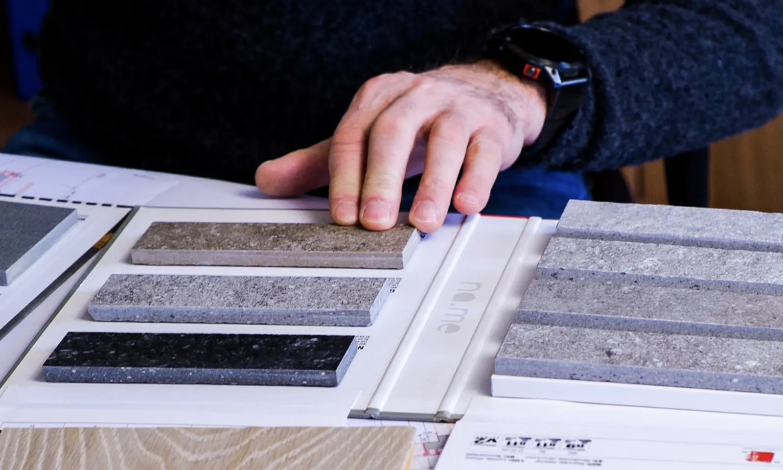 Una mano sceglie tra campioni di pietra per le finiture