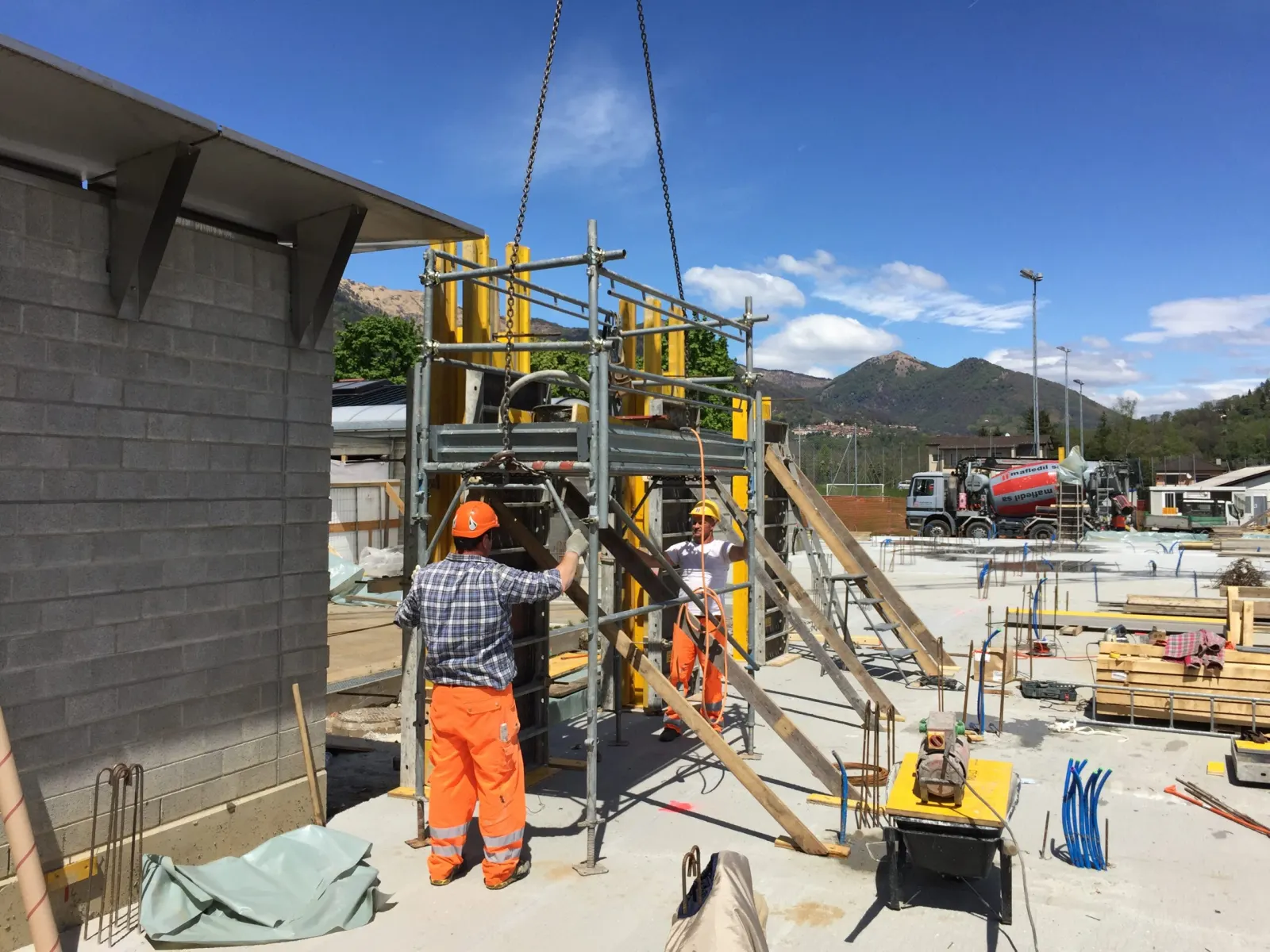 Operai in cantiere accanto a un montacarichi