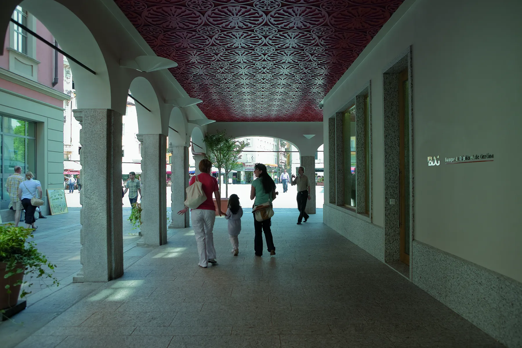 Passanti sotto un portico con soffitto decorato