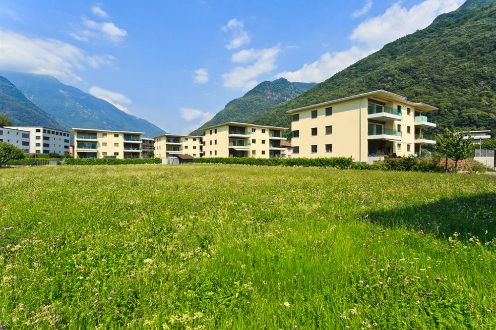 Palazzine residenziali davanti a un prato e alle montagne
