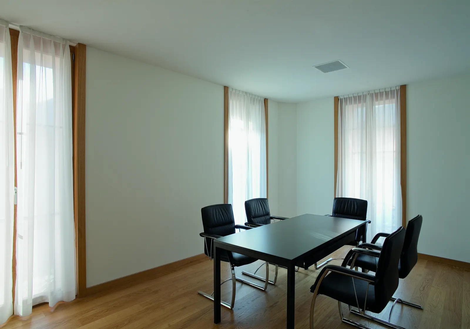Sala riunioni con tavolo scuro e tende chiare